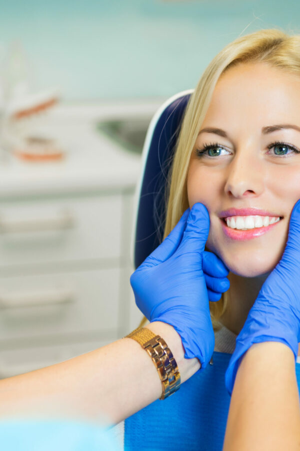 Female patient sitting in chair in dentist office for dental exam Female patient sitting in chair in dentist office for dental exam